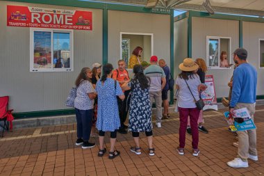 Civitavecchia, Italy - December 19, 2024: Group of people wait in line at ticket kiosk in Civitavecchia for Rome tours with shuttle services and hop-on hop-off bus and train tickets available. clipart