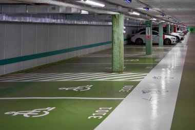 Madrid. Spain - January 19, 2025: Underground parking lot with reserved handicap spaces, green markings, and modern lighting. Ideal for urban settings and accessibility themes. clipart