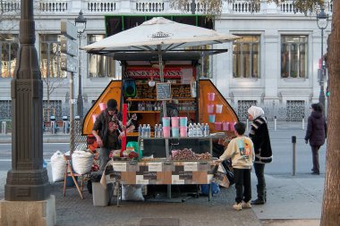 Madrid mi? İspanya - 20 Ocak 2025: Kavrulmuş bir kestane satıcısı Madrid caddesinde müşterilerle etkileşime geçiyor. Sahne yerel kültürü ve sokak piyasalarının cazibesini yansıtıyor.