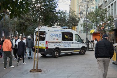 Madrid mi? İspanya - 22 Ocak 2025: Madrid belediye polisinden bir polis aracı kalabalık bir şehir bölgesinde konuşlandırıldı. İnsanlar, şehrin düzeni ve güvenliği sağlamadaki kararlılığını göstermek için araç yardım sağlarken yanımızdan geçiyorlar..