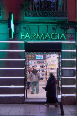 Madrid mi? İspanya - 23 Ocak 2025: Madrid 'de müşterilerle dolu canlı bir gece eczanesi, kentsel sağlık hizmetleri ve şehir yaşamını sergilemek için ideal. Kavram: Şehir sağlığı 
