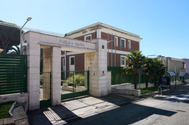 Civitavecchia. İtalya - 26 Ocak 2025: Civitavecchia, İtalya 'daki İtalyan Savaş Okulu' nun ana kapısı, üzerinde Scuola di Guerra işareti, yeşil çit ve arka planda kırmızı tuğla bina.