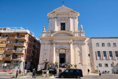 Civitavecchia, İtalya - 26 Ocak 2025: Civitavecchia, İtalya 'da St. Francis Katedrali heykeli ve haçı olan etkileyici neoklasik mimarisi ile. İnsanlar ve arabalar atmosfere hayat katıyor..