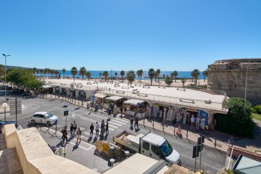 Civitavecchia. İtalya - 27 Ocak 2025: Yayalar, araçlar ve deniz kenarında canlı bir pazar alanının yer aldığı sokak manzarası. Kavram: Kentsel turizm ve kültür.