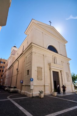Civitavecchia, İtalya - 27 Ocak 2025: Civitavecchia Kilisesi, güneşli bir cephe. Görüntü, park halindeki arabaları ve açık mavi gökyüzünü gösteriyor. İtalyan mimarisinin ve kültürünün güzelliğini vurguluyor..