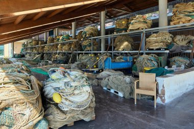 Büyük balık ağları ve ekipmanlar için liman kenarı depolama alanı. Kurulum, kıyı geçimlerini destekleyen balıkçılık altyapısının bir parçası.