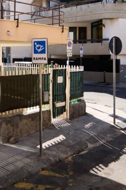 Catania, Sicilya 'da parlak bir şehir caddesi, engelli rampası işareti, yeşil kapı, ve park işareti yok, ulaşılabilirlik ve şehir hayatı teması için ideal..