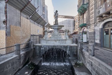 Catania, İtalya - 3 Mart 2025: Catania, Sicilya 'daki Amenano Çeşmesi, bir şehir kanalından aşağı dökülen su. Eski binalar ve mimari ve seyahat projeleri için iskelelerle çevrili..