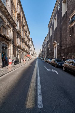 Catania 'da. İtalya - 04 Mart 2025: Sicilya Catania 'da canlı bir şehir caddesi, tarihi mimarisi, park edilmiş arabaları ve yayaları parlak Akdeniz semaları altında..