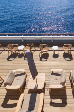 Rahat şezlonglar ve şemsiyelerle dolu, güneşli bir günde rahatlama ve sosyal etkinlikler için mükemmel bir teras..