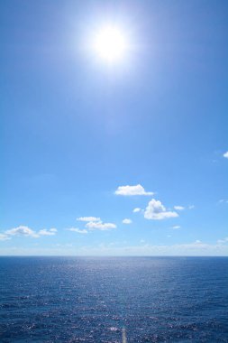 Lüks yolcu gemisinin güvertesinden açık mavi gökyüzünün altındaki engin okyanus manzarası. Huzurlu ve geniş deniz yolculuklarını resmetmek için mükemmel..