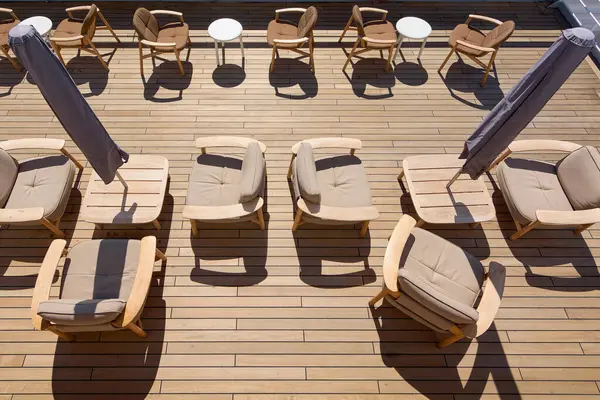 Ahşap döşemeleri, yastıklı sandalyeleri ve şemsiyeleri olan şık bir teras, açık hava eğlencesi ve güneşin tadını çıkarmak için ideal..