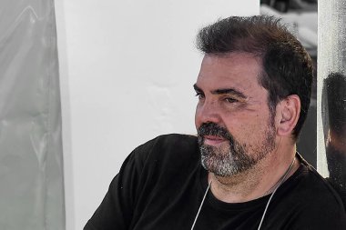 Siyah tişört ve altın kolye takan bir adamın odaklanmış fotoğrafı. Açık hava bulanık arka plan, kısa siyah saçlı..