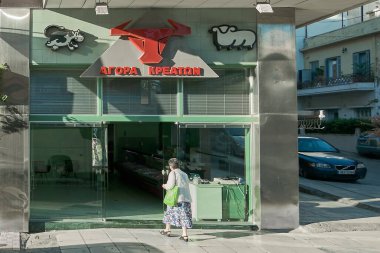 Girit. - Yunanistan - 27 Mart 2025: Yunanistan 'ın Girit kentindeki geleneksel kasap dükkanı, kırmızı bir boğa başı logosu, Yunan metni ve dükkanın giriş tabelasında inek ve koyun resimleri yer alıyor..
