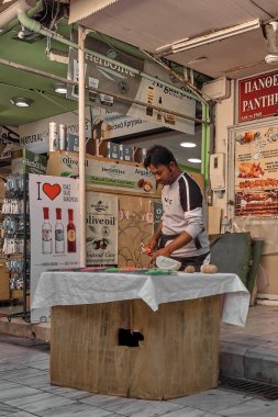 Girit, Yunanistan - 5 Nisan 2025: Canlı bir açık hava pazarında sebze ve tanıtım tabelalarıyla mutfak aletinin tanıtımı.