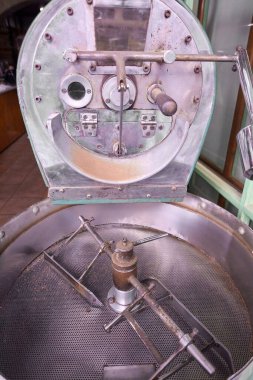 Profesyonel kahve kızartma sürecinde kullanılan endüstriyel kahve kızartma makinesinin mekanik bileşenlerini ve yapısını vurgulayan yakın çekim görüntüsü.