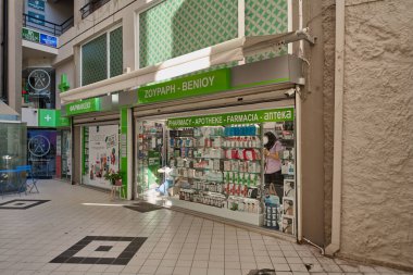 Crete.Yunanistan - Nisan 03, 2025: Çeşitli tıbbi ve sağlık ürünleri çeşitliliğine sahip çok dilli ve PHARMACY gibi işaretleri olan şehir eczanesi.