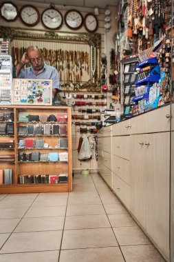 Girildi. Yunanistan - Nisan 03, 2025: Cüzdan, kemer, saat ve saatlerin sergilendiği bir aksesuar dükkanının içi, tezgaha katılan bir kişi ile düzenli bir şekilde düzenlendi..