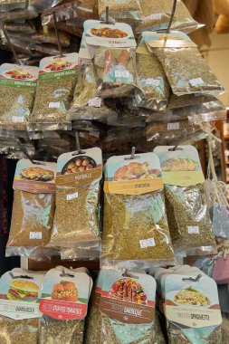 Girit, Yunanistan - 5 Nisan 2025: Barbekü, pizza, köri ve salata karışımları da dahil olmak üzere pişirme için bitki karışımlarının renkli bir dükkan ortamında temiz etiketlerle dolu canlı poşetlerde sergilenmesi.