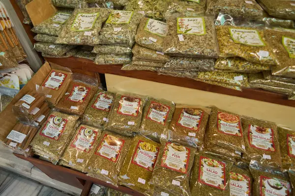 Girit, Yunanistan - 5 Nisan 2025: Canlı baharat dükkanı barbekü çeşnisi, pizza sosu otları ve köri karışımları gibi temel yemek pişirme malzemelerini açık bir şekilde etiketlenmiş ve düzgünce istiflenmiş şekilde sergiliyor.