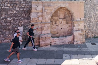 Girit, Yunanistan - 7 Nisan 2025: Osmanlı döneminden kalma bir yapı olan Jenitsar Ağa Çeşmesi, karmaşık oymalar, çiçek desenleri ve taş bir duvara dayanan dekoratif oymalar içeren kemerli bir tasarıma sahiptir.