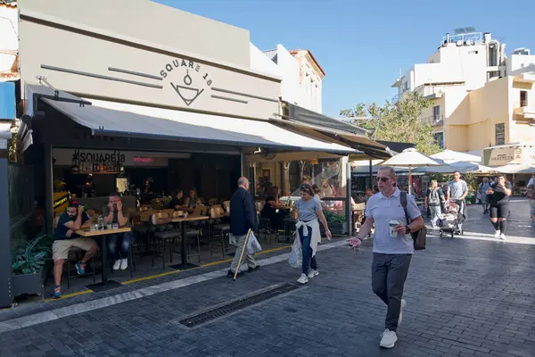 Girit, Yunanistan - 7 Nisan 2025: Heraklion 'daki 18 numaralı meydan restoranında açık hava oturma, kaldırım taşı cazibesi, modern mimari ve yerli ve turistlerin ilgisini çeken canlı bir atmosfer yer alıyor..