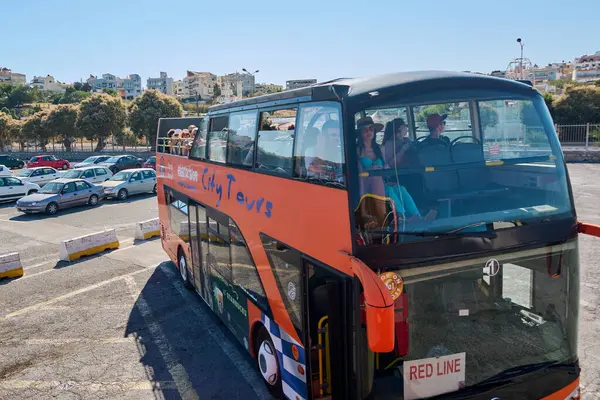 Girit. Yunanistan - Nisan 07, 2025: Girit 'in hareketli bir bölgesine park etmiş canlı bir turist otobüsü, yerel gezinin ve Akdeniz cazibesinin özünü yakalıyor..