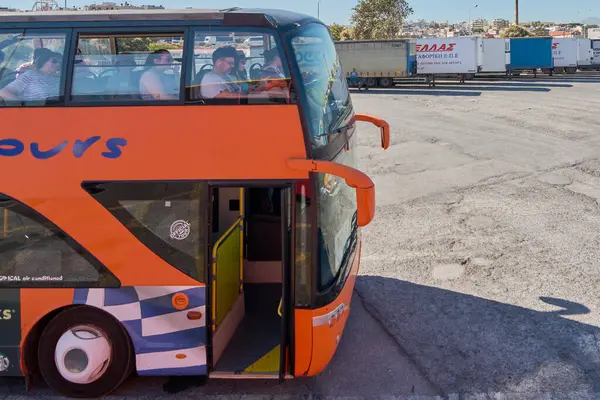 Girit, Yunanistan - 7 Nisan 2025: Şehir Turları ve RED LINE etiketli kırmızı çift katlı turist otobüsü, arka planda otomobiller ve ağaçlarla birlikte, keşfedilmeye hazır..