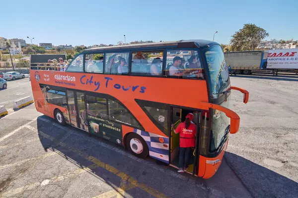 Girit, Yunanistan - 7 Nisan 2025: Canlı bir turizm otobüsü Heraklion hareketli caddelerinin ortasında duruyor. Açık-üstü tasarımı panoramik görüntüler sunuyor, Girit simgelerinin araştırılmasını teşvik ediyor.