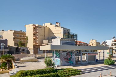 Girit. Yunanistan - 11 Nisan 2025: Girit 'te solmuş duvarları, duvar yazıları ve kırık camları olan yıpranmış bir otel. Terk edilmiş yapı, kentsel bozulmayı ve tarihi vurgulayan parlak gökyüzü ile çelişiyor..