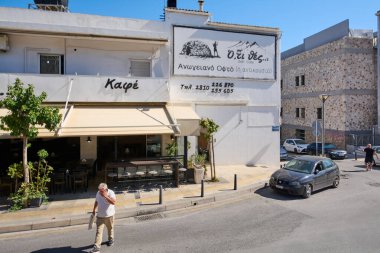 Girit. Yunanistan - 11 Nisan 2025: Girit 'te açık oturaklı bir karşılama kafe ve restoranı. Yunan tabelası, rahat ışıklandırma ve büyüleyici bir teras yerel halk ve ziyaretçiler için davetkar bir atmosfer yaratıyor