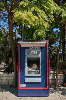 Girit. Yunanistan - 23 Nisan 2025: Görünür tabela ve güvenli erişim içeren modern bir açık hava ATM makinesi. Sokak mobilyalarının yanına yerleştirilmiş, yerel halka hizmet veriyor ve ziyaretçilerin hızlı bir banka transa ihtiyacı var.