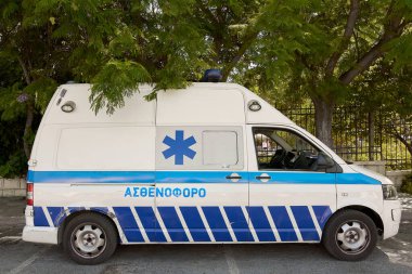 Crete. Yunanistan - 23 Nisan 2025: Resmi tıbbi işaretli beyaz bir ambulans şehir caddesinde park halinde. Mavi yaşam sembolü, acil tıbbi müdahale hizmetlerinin...