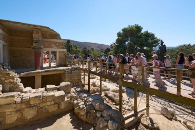 Girit. Yunanistan - 26 Nisan 2025: Knossos Sarayı 'nın kalıntılarını araştıran ziyaretçiler, Minos medeniyetinin canlı mavi gökyüzü altında yeniden inşa edilmiş detaylarla mimari güzelliğini sergilediler..