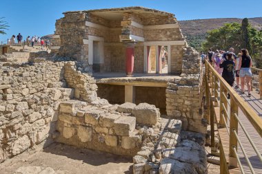 Girit. Yunanistan - 26 Nisan 2025: Knossos 'un antik kalıntılarının çarpıcı manzarası, tarihi taş mimarisi ve açık mavi gökyüzü altında kültürel mirasın ortasında duran kırmızı sütunlar..