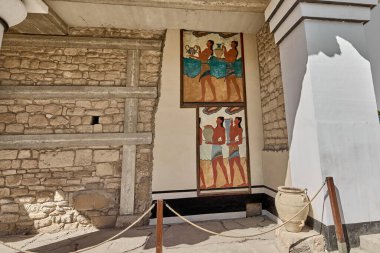 Antik bir taş duvarın üzerinde canlı şekilde boyanmış iki fresk, Knossos 'taki ilk medeniyetin sanat ve zanaatkarlığını sergileyen, gemi taşıyan Minos figürlerini resmediyor..