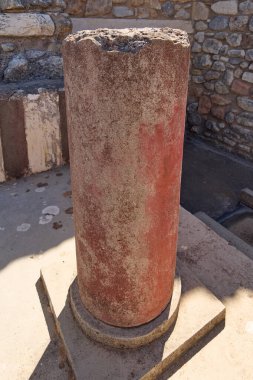 Canlı kırmızı bir sütun, Yunanistan 'ın en ikonik arkeolojik sahalarından birinin zanaatkarlığını ve mirasını yansıtan Knossos Sarayı' nın antik taş çevresiyle çelişiyor..