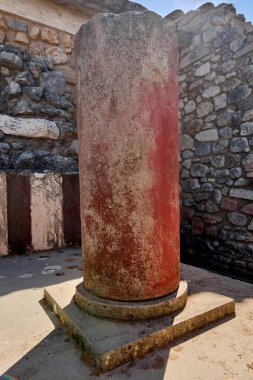 Knossos Sarayı 'nın çarpıcı kırmızı sütunu yıpranmış taş kalıntıları arasında duruyor. Minos medeniyetinin tarihi sanat ve mimari detaylarını gözler önüne seriyor..