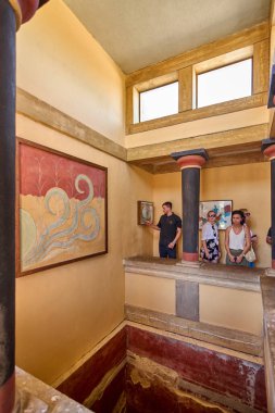 Girit. Yunanistan - 05 Mayıs 2025: Bir grup turist Knossos Sarayı 'nın iç kısımlarından geçerek, antik Yunan tarihine gömülmüş kırmızı ve siyah sütunlarını ve Minos mimari unsurlarını gözlemlediler..