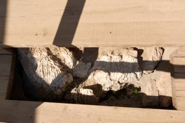 Tahta kirişler ve taş tabakaları, antik kaya oluşumları ve modern restorasyon teknikleri arasındaki zıtlığı gözler önüne sererek, Knossos Sarayı 'nda devam eden kazı çalışmalarını ortaya koyuyor..