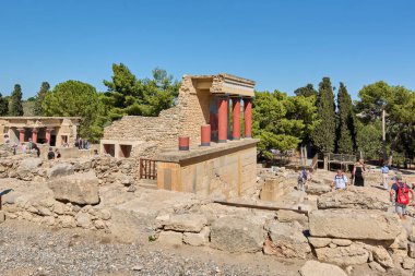 Girit. Yunanistan - 05 Mayıs 2025: Knossos Sarayı 'nın antik kalıntıları, yıpranmış taş duvarlar arasında Minos medeniyetinin mimari dehasını vurgulayarak, restorasyon çabalarıyla korunan kırmızı ve siyah sütunları sergilemektedir..