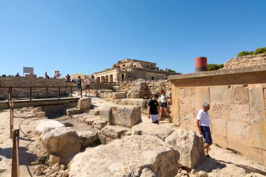 Girit. Yunanistan - 05 Mayıs 2025: Ziyaretçiler, kısmen restore edilmiş harabelerinde canlı kırmızı sütunlar ve Akdeniz güneşi altında solmuş fresklerin bulunduğu Knossos Sarayı 'nı keşfediyorlar..