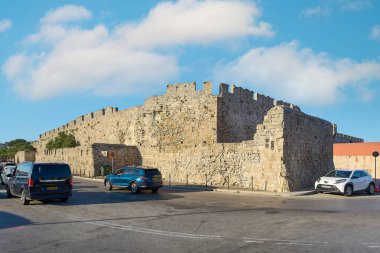 Girit. Yunanistan 15 Mayıs 2025: Rodos 'ta etkileyici siperleri ve iyi korunmuş taş yapısı olan görkemli ortaçağ duvarı. Etrafı park etmiş arabalarla çevrili, açık mavi bir gökyüzünün altında..