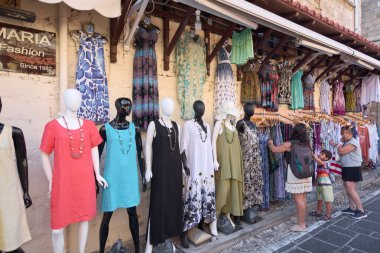 Rodas.Yunanistan - 22 Mayıs 2025: Tarihsel bir ortamda canlı bir açık hava giyim mağazası, çeşitli yaz elbiseleri sergilenen mankenler,