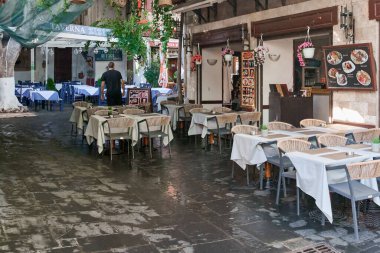 Rhodes. Yunanistan 24 Mayıs 2025: Büyüleyici bir restoran terasının ayrıntıları, kırsal hasır hasır lambaları ve bol yeşillikleri vurguluyor, rahat ve otantik bir Akdeniz atmosferine katkıda bulunuyor.