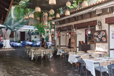 Rhodes. Yunanistan 24 Mayıs 2025: Huzurlu bir ortamda yerel mutfaktan keyif almak için ideal geleneksel mimari ve doğal dekorun bir karışımını sergileyen bir Yunan lokantasında güzel bir açık hava alanı.