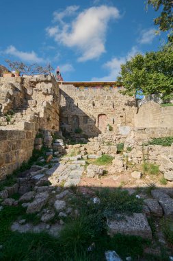 Rhodes Eski Kasabası 'nda taş duvarlar ve tarihi kalıntılar. Parçalı bulutlu bir gökyüzünün altında antik duvarların zengin dokusunu sergiliyorlar..