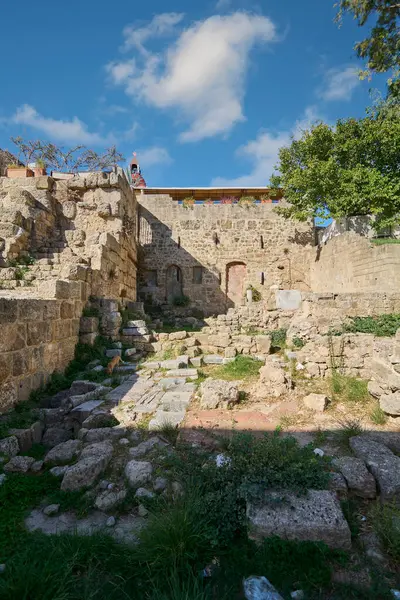 Rhodes Eski Kasabası 'nda taş duvarlar ve tarihi kalıntılar. Parçalı bulutlu bir gökyüzünün altında antik duvarların zengin dokusunu sergiliyorlar..