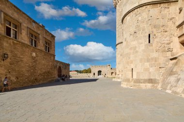 Rodas.Yunanistan - Haziran 01, 2025: Antik taş duvarlarla çevrili tarihi güçlendirilmiş komplolar ve parlak bir gökyüzü altında yükselen dairesel yapı