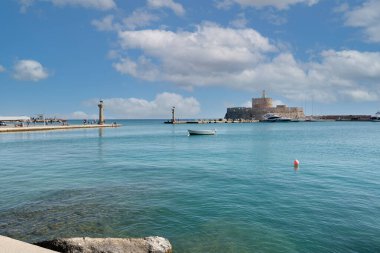 Rodas.Yunanistan - Haziran 04, 2025: Rodos 'taki Mandraki Limanı' nın panoramik manzarası, tarihi Aziz Nicholas Kalesi ve mavi gökyüzü altındaki ikonik deniz fenerleri.
